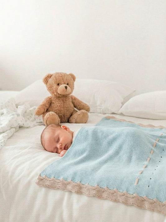 Neonato che dorme con la copertina Mac Ilusion azzurra e un orsetto