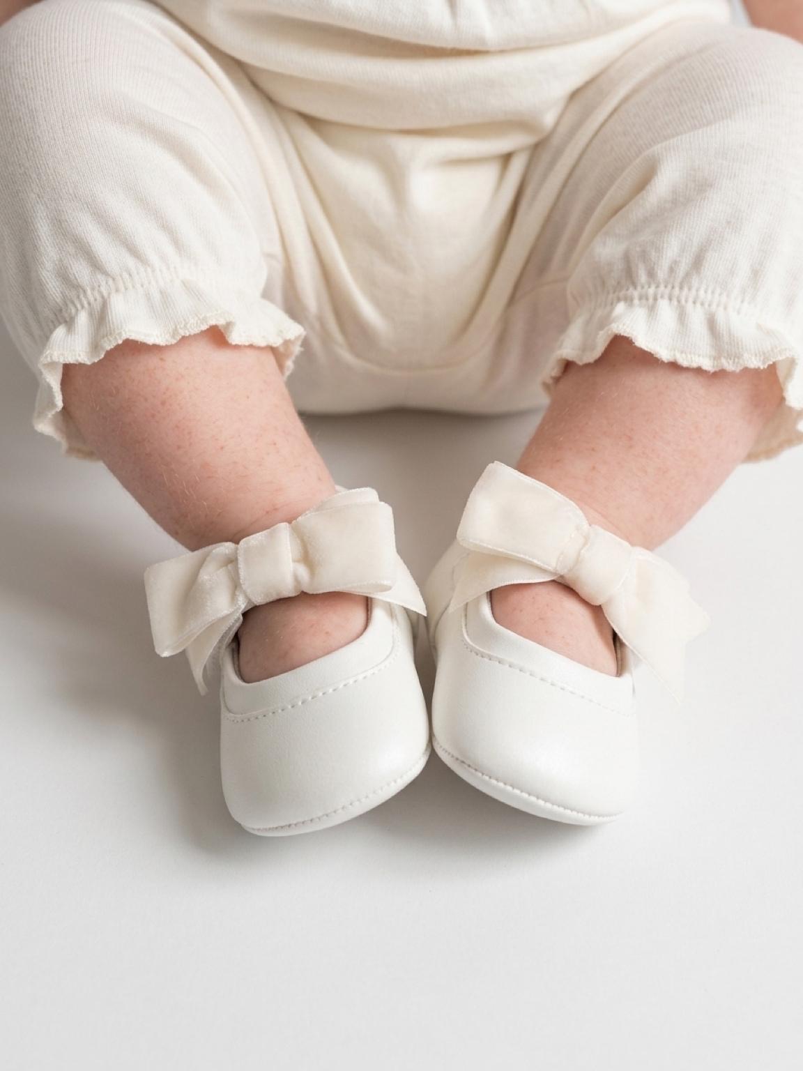Neonata seduta che indossa le scarpine Mayoral Newborn con fiocco