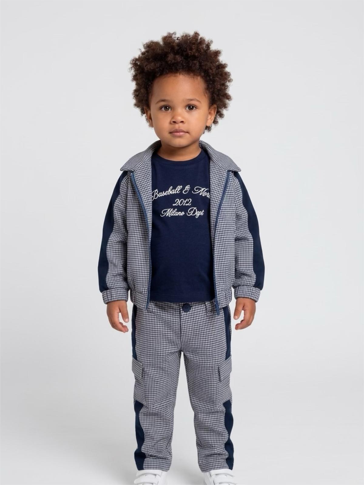 Bambino che indossa il completo Never Too con giacca a quadretti, t-shirt blu e pantalone