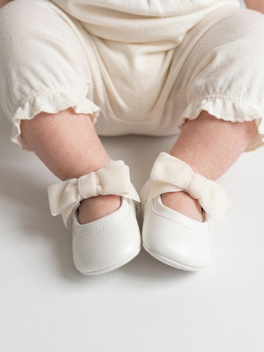Neonata seduta che indossa le scarpine Mayoral Newborn con fiocco